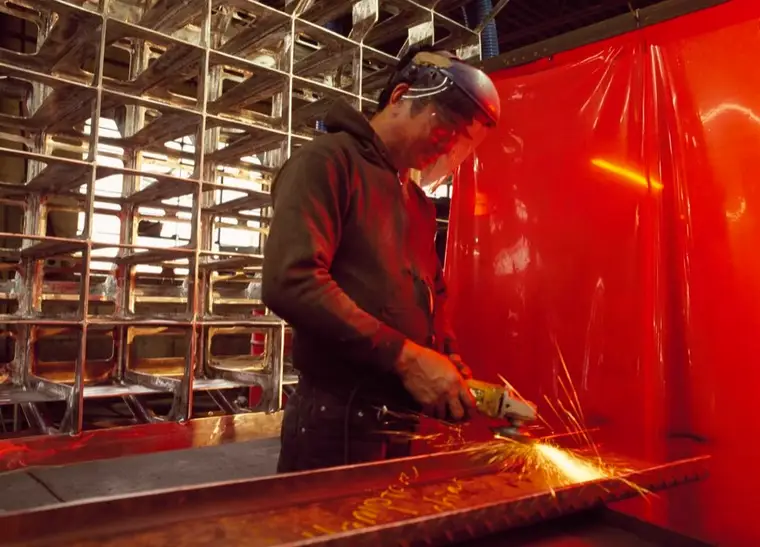 A modern industrial worker photographed in a workshop, with tools and machinery around him